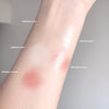 Arm with different colored makeup swatches on a neutral background