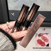 Two lipsticks and their packaging held by a hand, with a close-up of the lipstick on skin.