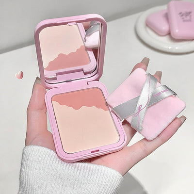 Pink makeup compact with mirror held by a hand, close-up of eye, and blurred background.