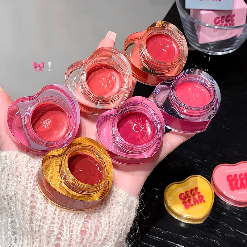 Hand holding multiple small jars of pink lip gloss with 'Geece Bear' branding.