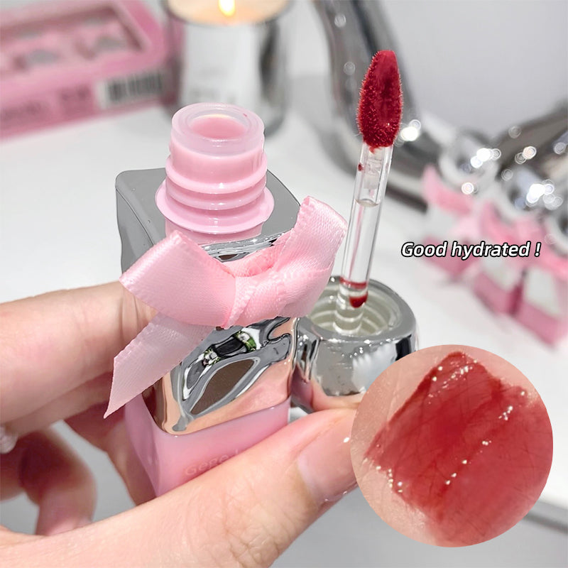 Pink lip gloss with applicator and swatch on a blurred background