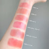 Lipstick swatches on a person's arm with color names labeled.