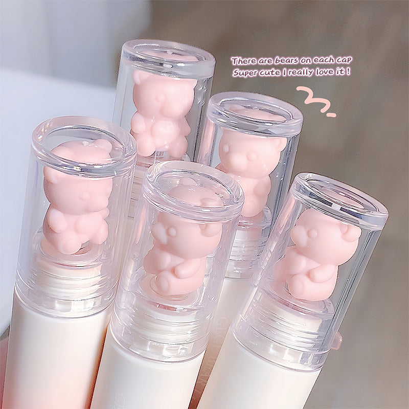 Set of lip balms with bear-shaped caps on a light background