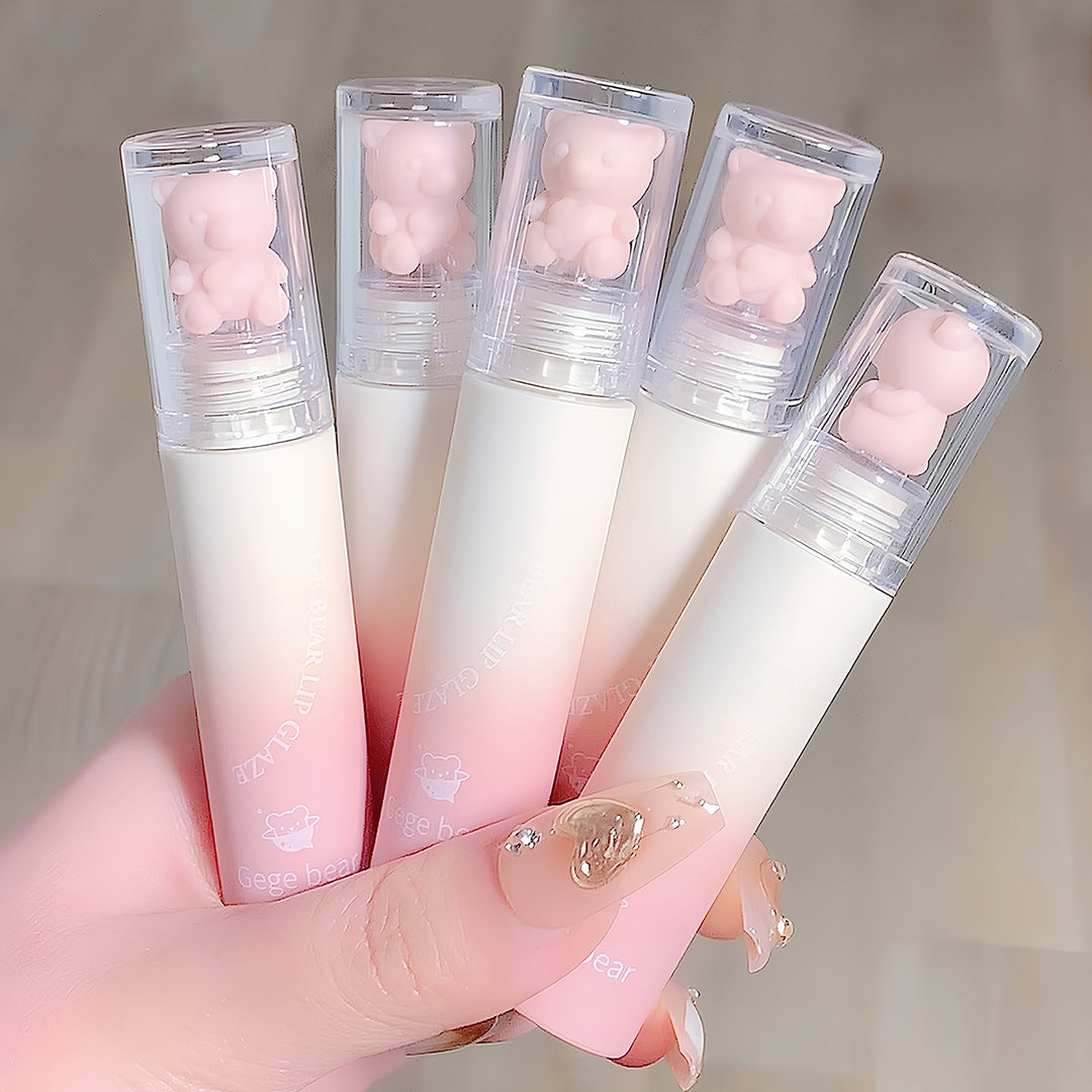 Five gradient lip balms with bear-shaped caps held by a hand against a neutral background