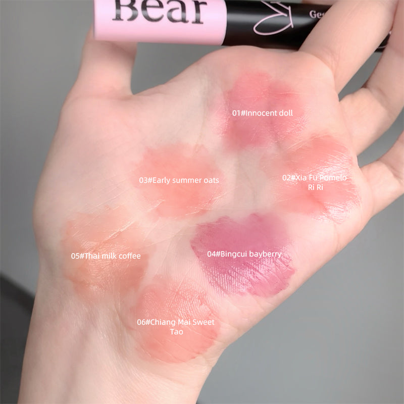 Hand with lipstick swatches labeled with color names and a 'Bear' product in the background.