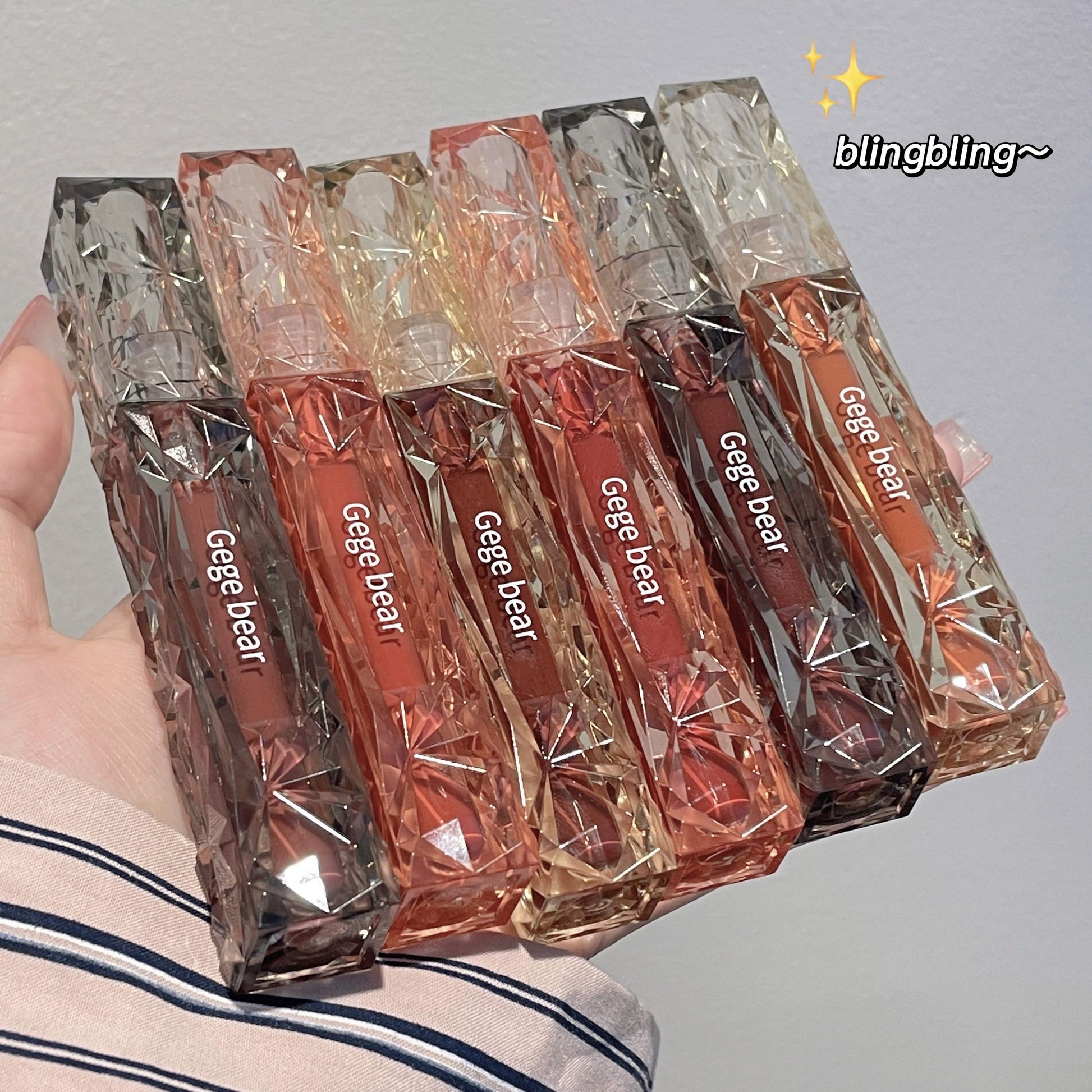 Packaged lip products with 'Gege bear' branding held by a hand against a neutral background.