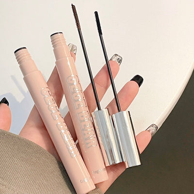 Makeup products including mascara and eyeliner held by a hand on a neutral background