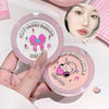 Two compact powder cases with cartoon designs and a hand holding one of them.
