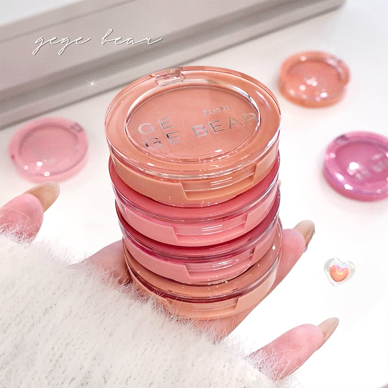 Stack of pink makeup products with 'Gige Bear' branding held by a hand.