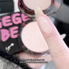 Hand holding a compact powder with a blurred background