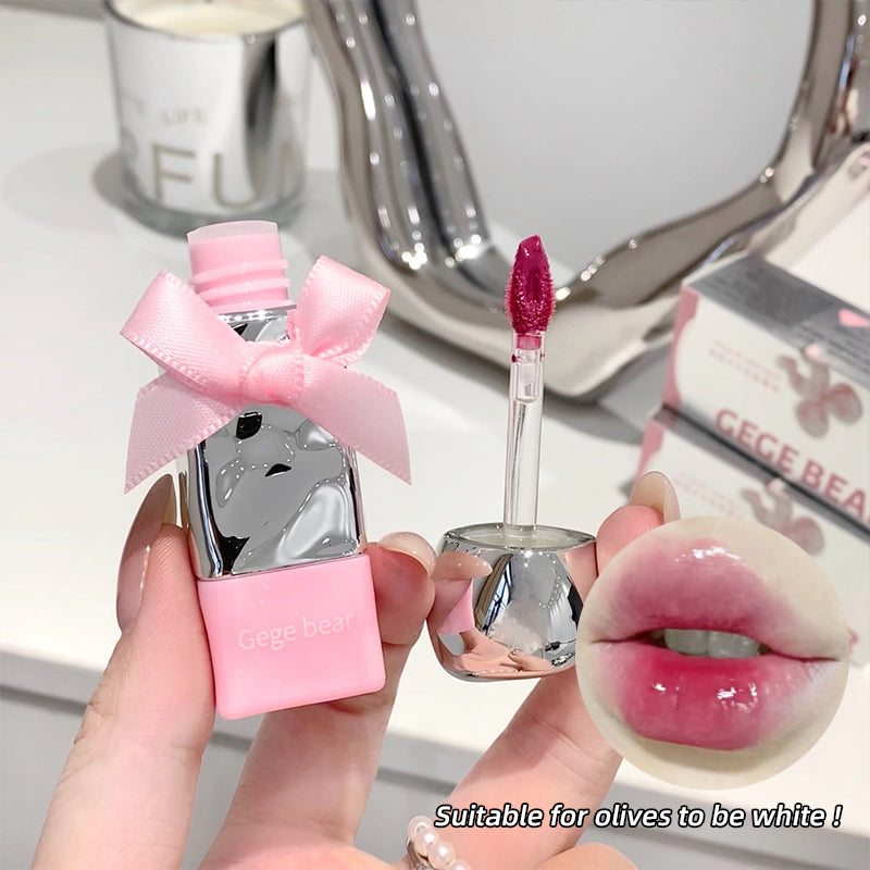 Pink lip gloss with a bow and applicator, held by a hand, with a close-up of lips wearing the gloss.