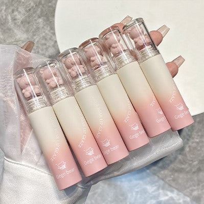 Set of gradient lip glosses held by a hand with a neutral background
