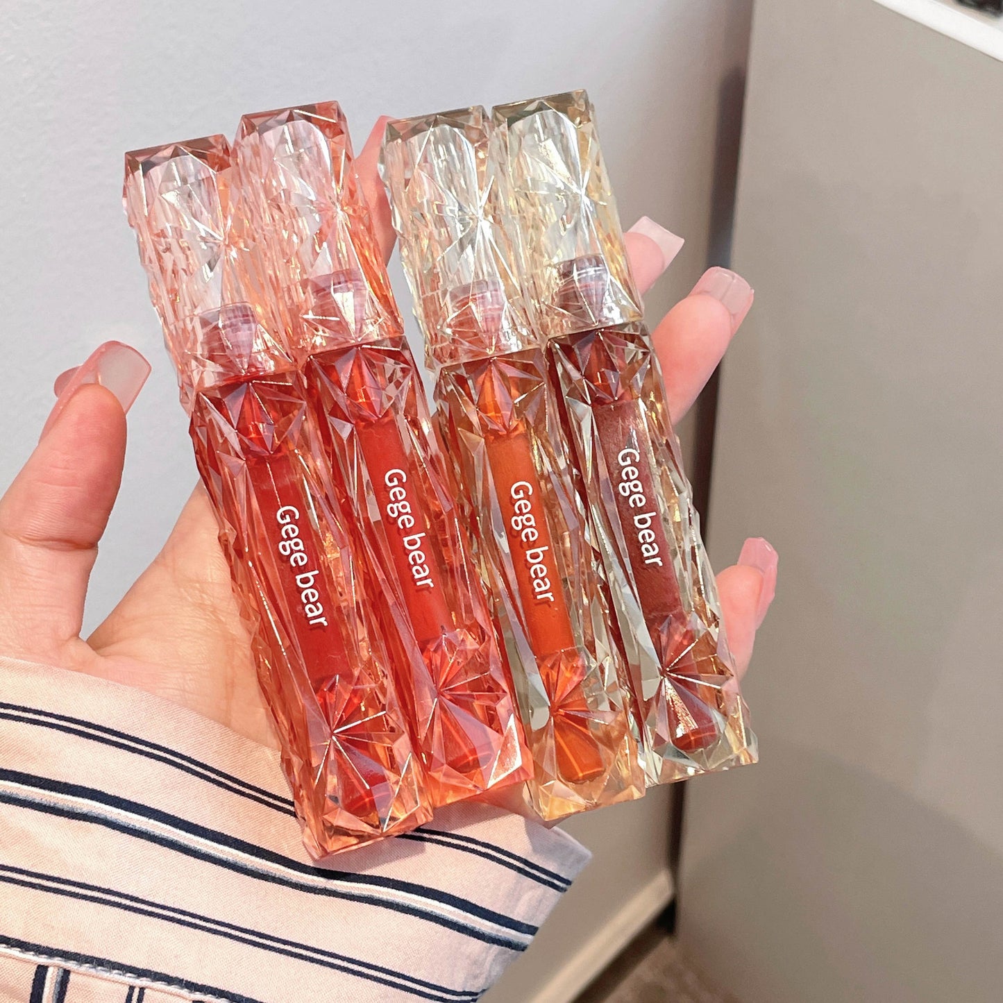 Hand holding four transparent packages of 'Gegebear' products against a neutral background
