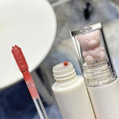 Lip gloss with applicator and bear-shaped cap on a blurred background