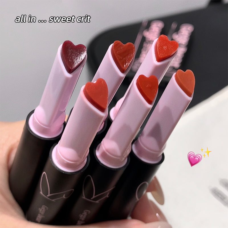 Set of lipsticks with heart-shaped caps held by a hand, with text 'all in ... sweet crit' above.