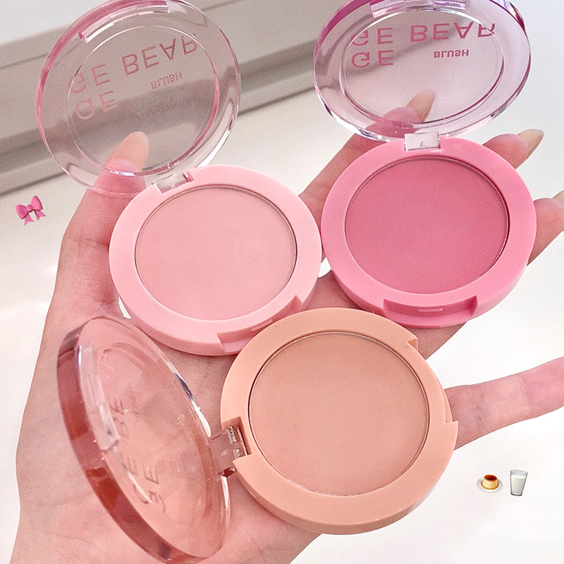 Hand holding three pink makeup compacts with 'Bebe' branding.