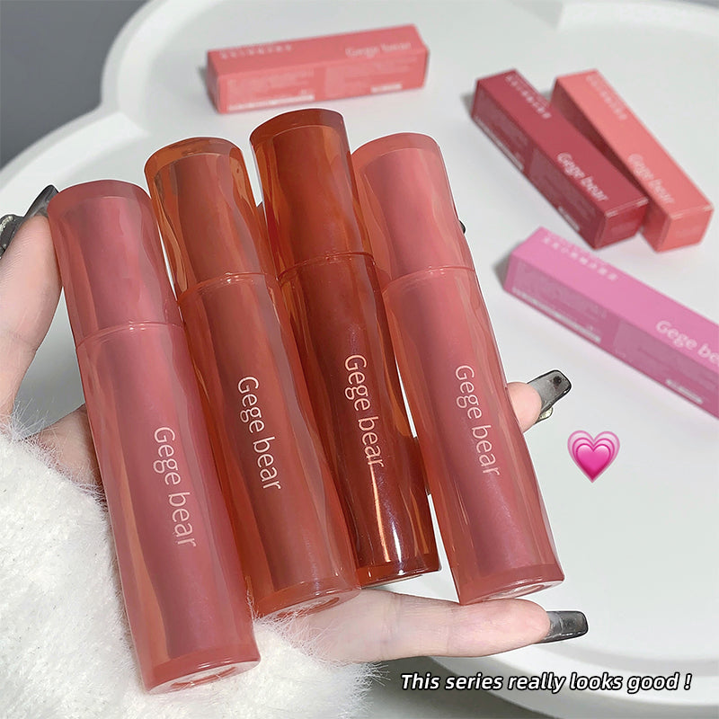 Four Gege bear lipsticks held by a hand on a white surface with additional lipsticks in the background.