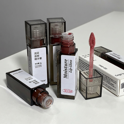 Lip gloss products with visible labels on a white surface
