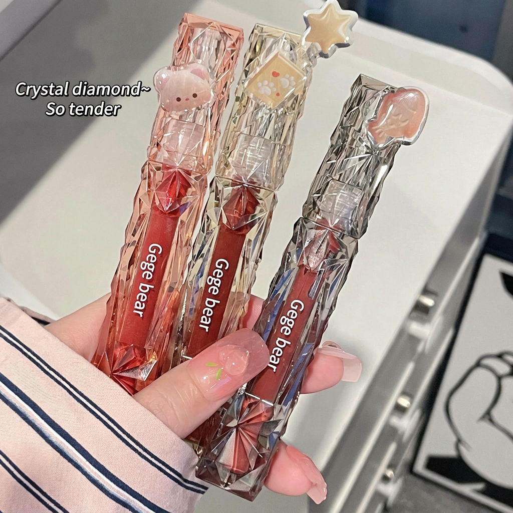 Three transparent lip glosses with bear and star designs held by a person.