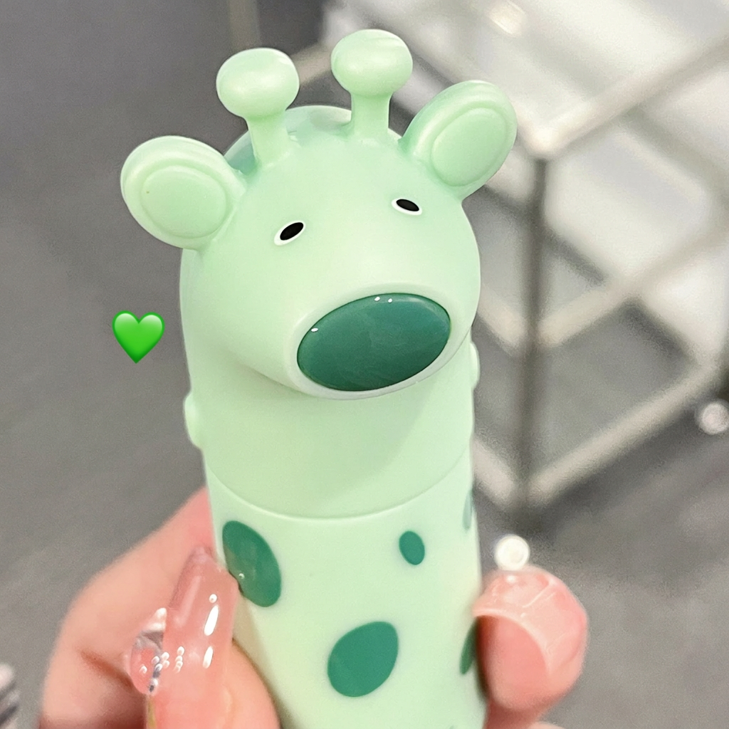 Green cartoon character with polka dots held by a hand