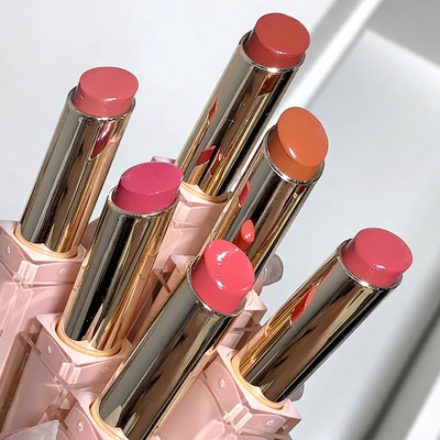 Set of lipsticks with pink and orange caps in a pink holder on a white background