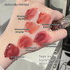 Hand with multiple shades of lip gloss swatched on a white background, labeled with product names.