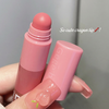 Pink lip balm with a crayon tip held by a hand against a gray background