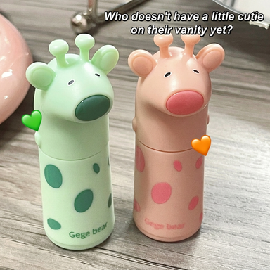 Two cartoon-themed lip balms, one green and one pink, on a wooden surface with text overlay.