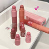 Set of pink lip crayons on a white surface with a box in the background.