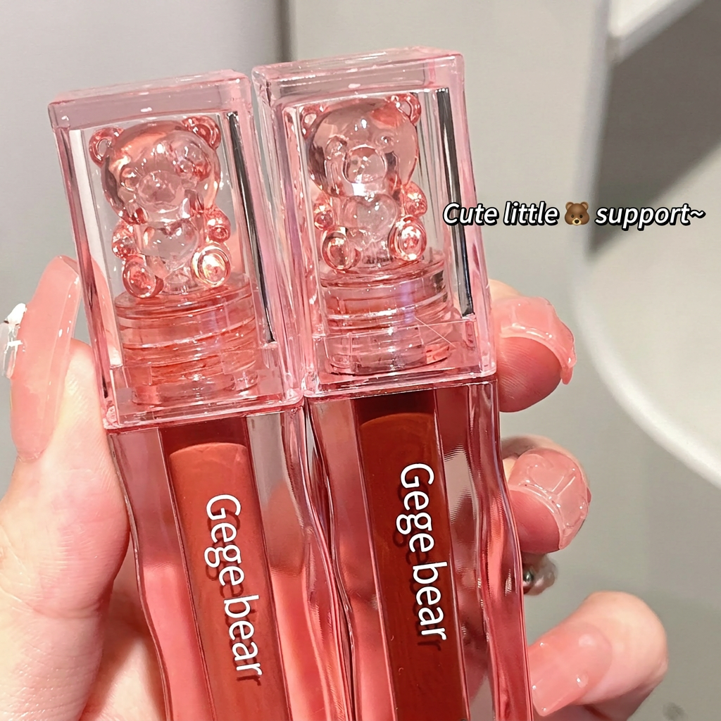 Two pink lip glosses with bear design in clear cases held by a hand.