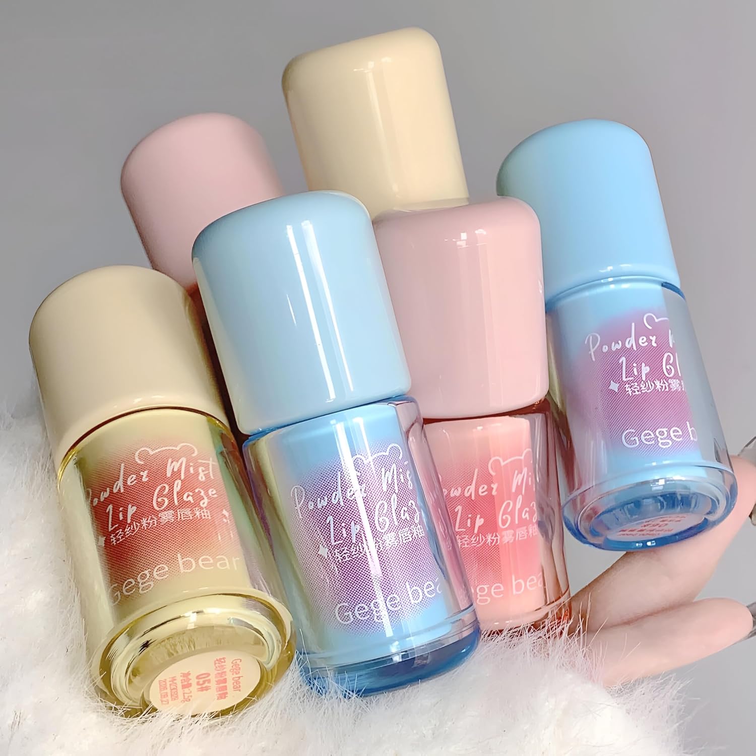 Five small bottles of 'Geege bear' powder lip glaze on a light gray background